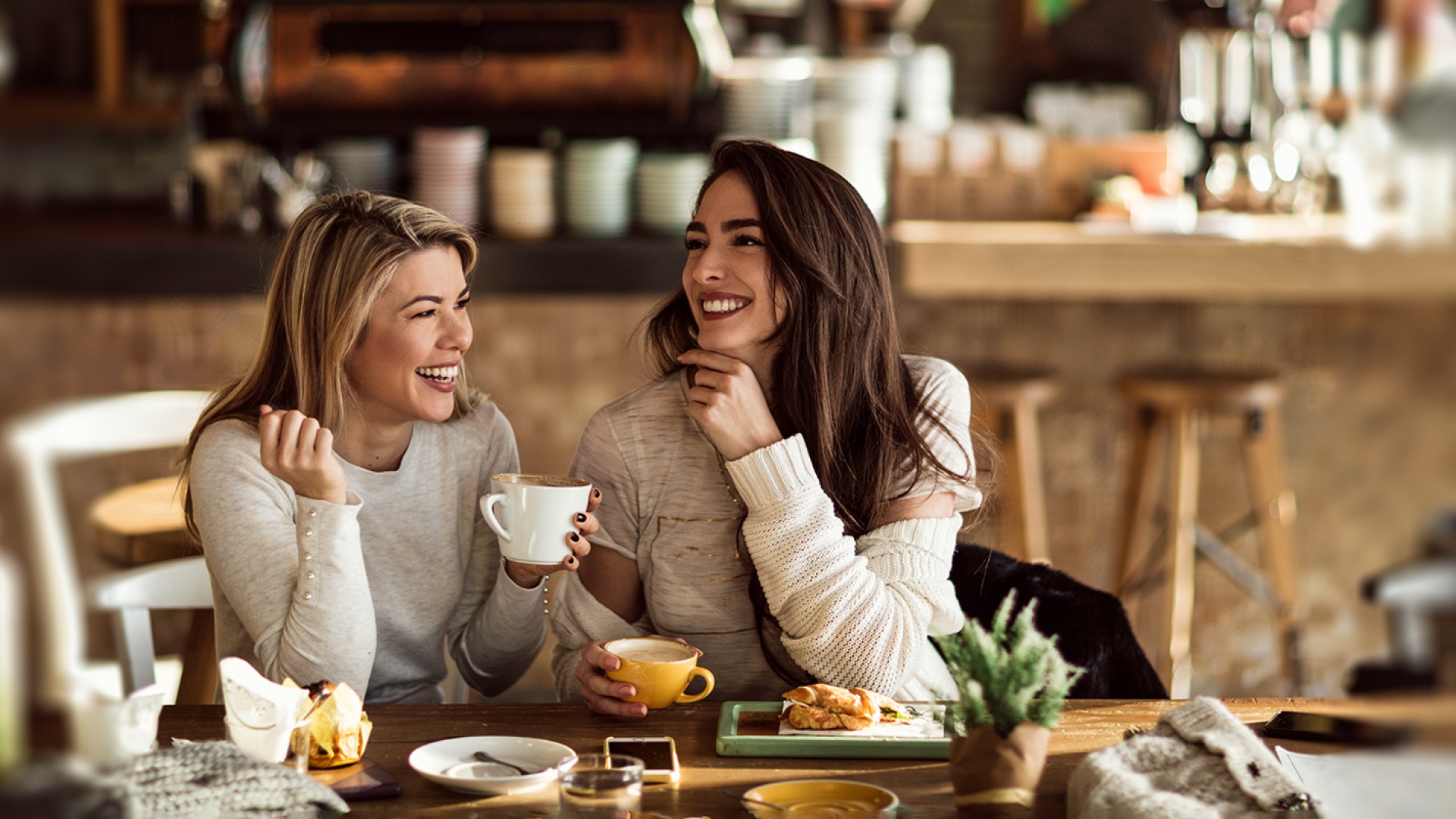 Two cheerful women having fun during coffee time in a cafe.